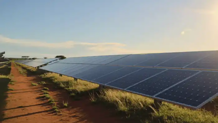 Fileiras de módulos fotovoltaicos de 550W recebendo forte incidência solar em campo aberto sob o céu do Cerrado